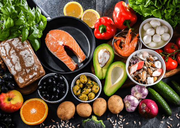 Spread of Mediterranean diet foods including salmon, bread, vegetables, olives and seafood