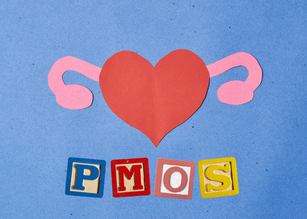Paper-cut illustration of a red heart with pink wing shapes above wooden letter tiles spelling PMOS
