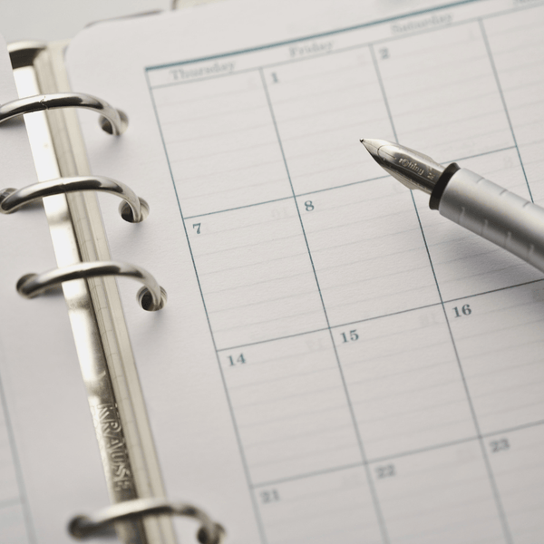 Silver fountain pen resting on an open desk planner