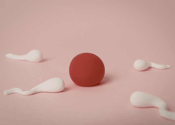 Clay illustration of a red ball surrounded by white sperm shapes on a pink background