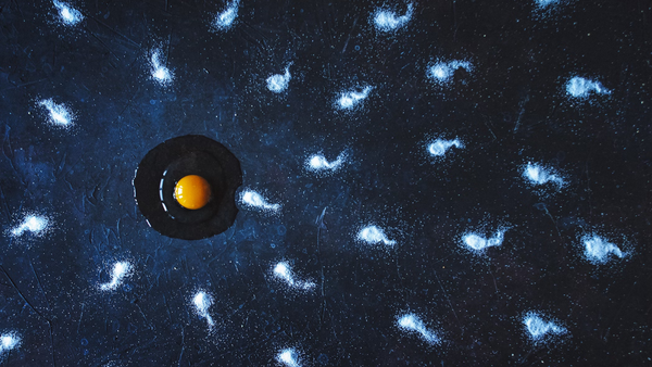 Cracked egg yolk on a dark surface surrounded by scattered salt crystals