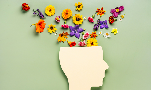 Paper cutout of a head with colourful flowers blooming from the top