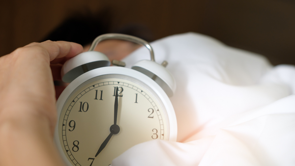 Hand reaching to switch off an alarm clock while in bed