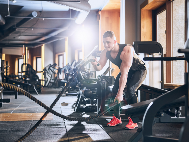 Man performing battle rope exercises in a gym