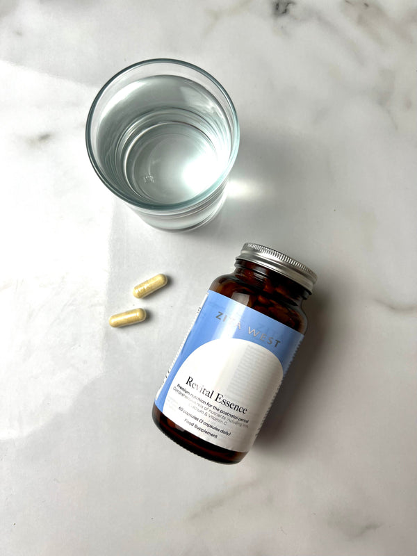 Zita West Revital Essence supplement bottle with capsules and a glass of water