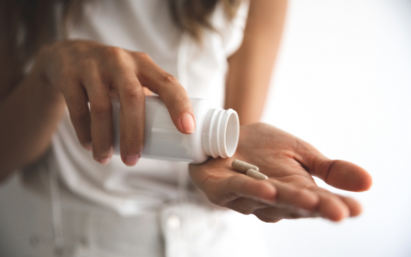 Woman pouring supplement capsules from a bottle into her hand