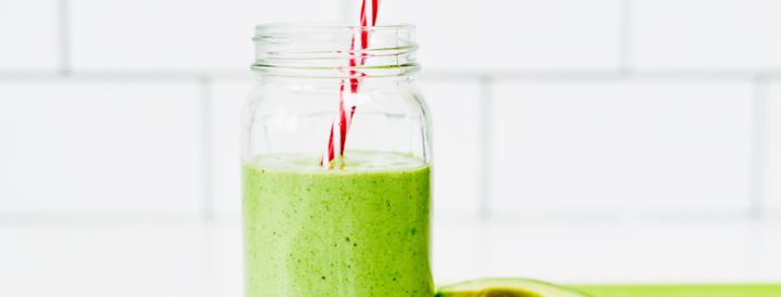 Green avocado smoothie in a mason jar with striped straws
