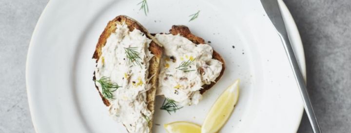 Mackerel pâté on toasted bread garnished with dill and served with lemon wedges