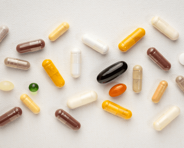 Assorted colorful supplement capsules scattered on a white surface