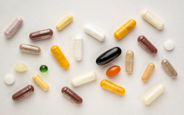 Assorted vitamin and supplement capsules scattered on a fabric surface