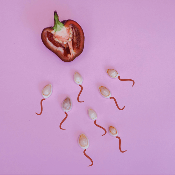 Halved red pepper with seeds shaped like sperm on a pink background