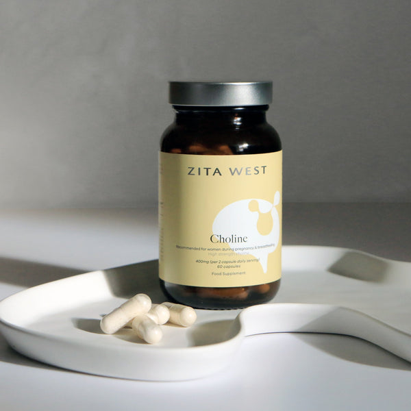 Zita West Choline supplement bottle on a white dish with loose capsules