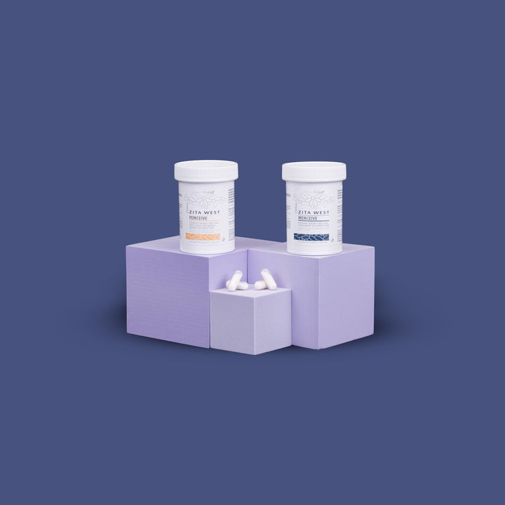 Two Zita West Ferceive supplement bottles displayed on lilac blocks against a navy background