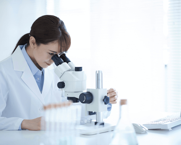 Female scientist in a lab coat looking into a microscope