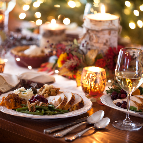 Festive dinner table with roast turkey, vegetables and a glass of white wine