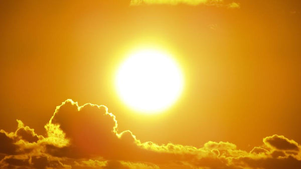 Bright sun shining through golden clouds at sunset