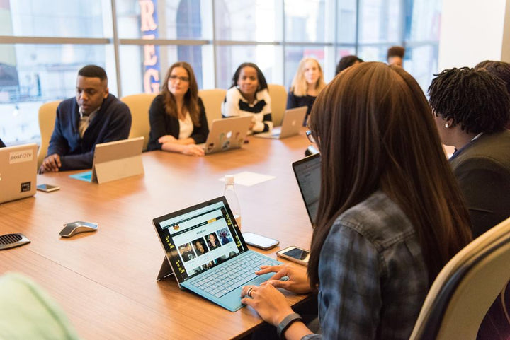 People sitting around a conference table with laptops during a workplace meeting