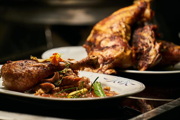 Roasted chicken leg garnished with an edible flower on a decorative plate