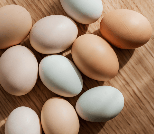 Assorted brown, white and pale blue eggs on a wooden surface