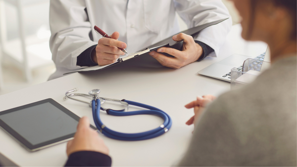 Doctor writing on a clipboard while speaking with a patient