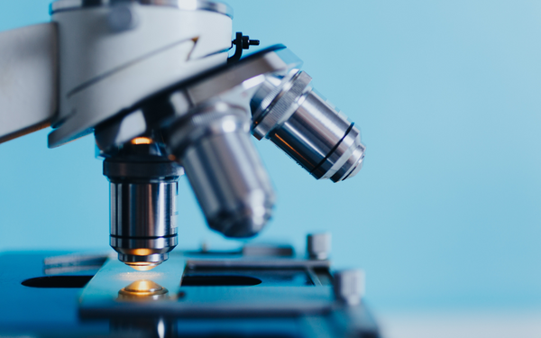 Close-up of a microscope's lenses against a blue background