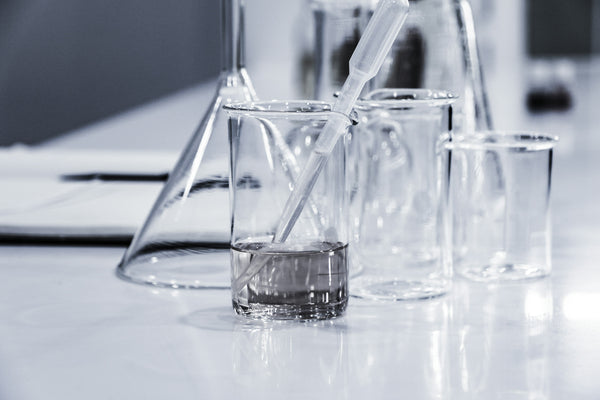 Laboratory beakers and a pipette with liquid samples on a lab counter