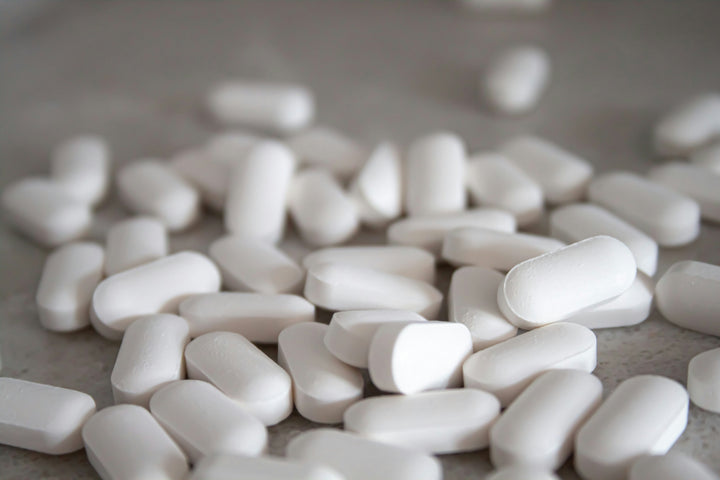 Close-up of scattered white tablets on a grey surface