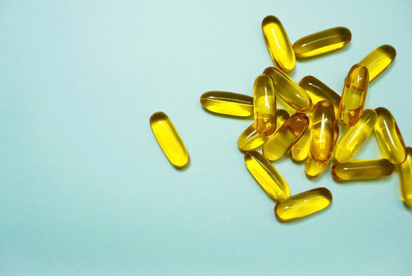 Close-up of yellow supplement capsules on a light blue background