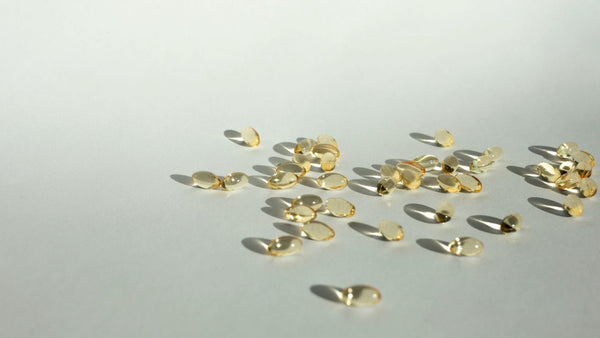 Yellow oil supplement capsules scattered on a white surface