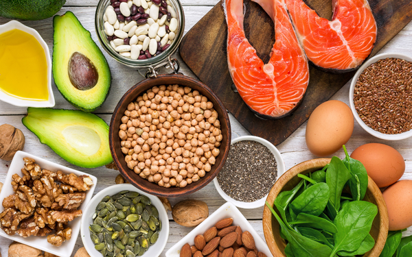 Assorted omega-3 rich foods including salmon, avocado, nuts, seeds and spinach