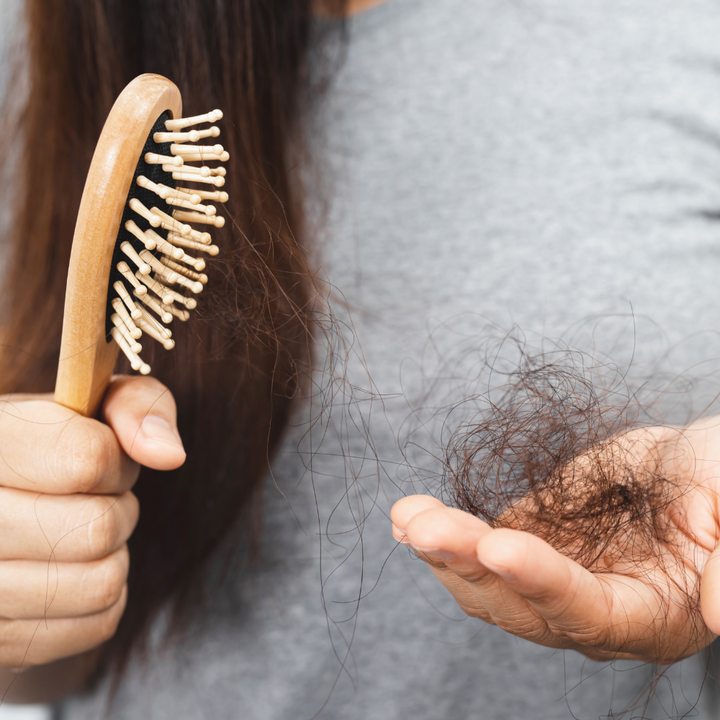 Woman holding a hairbrush and a handful of shed hair in her palm