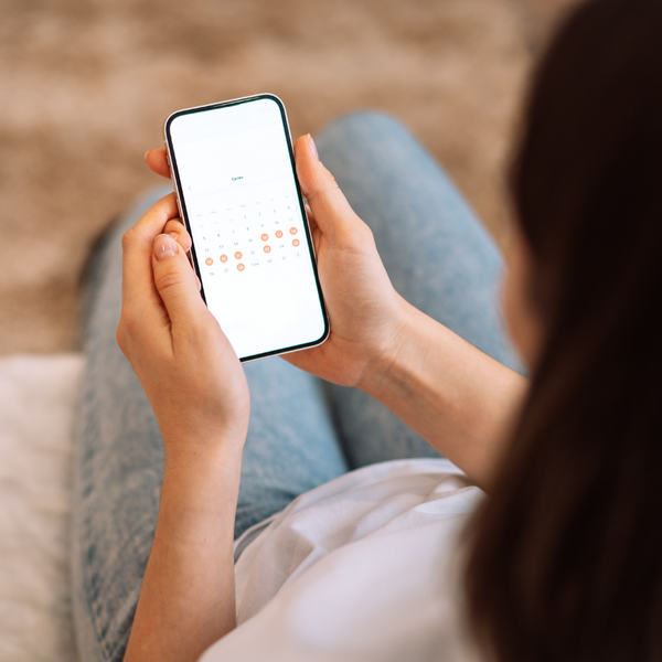 Woman looking at a period tracking calendar app on her phone