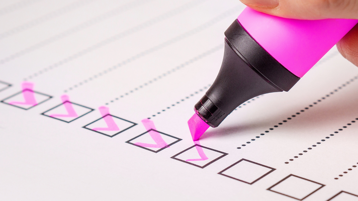Pink highlighter marker checking off boxes on a printed checklist