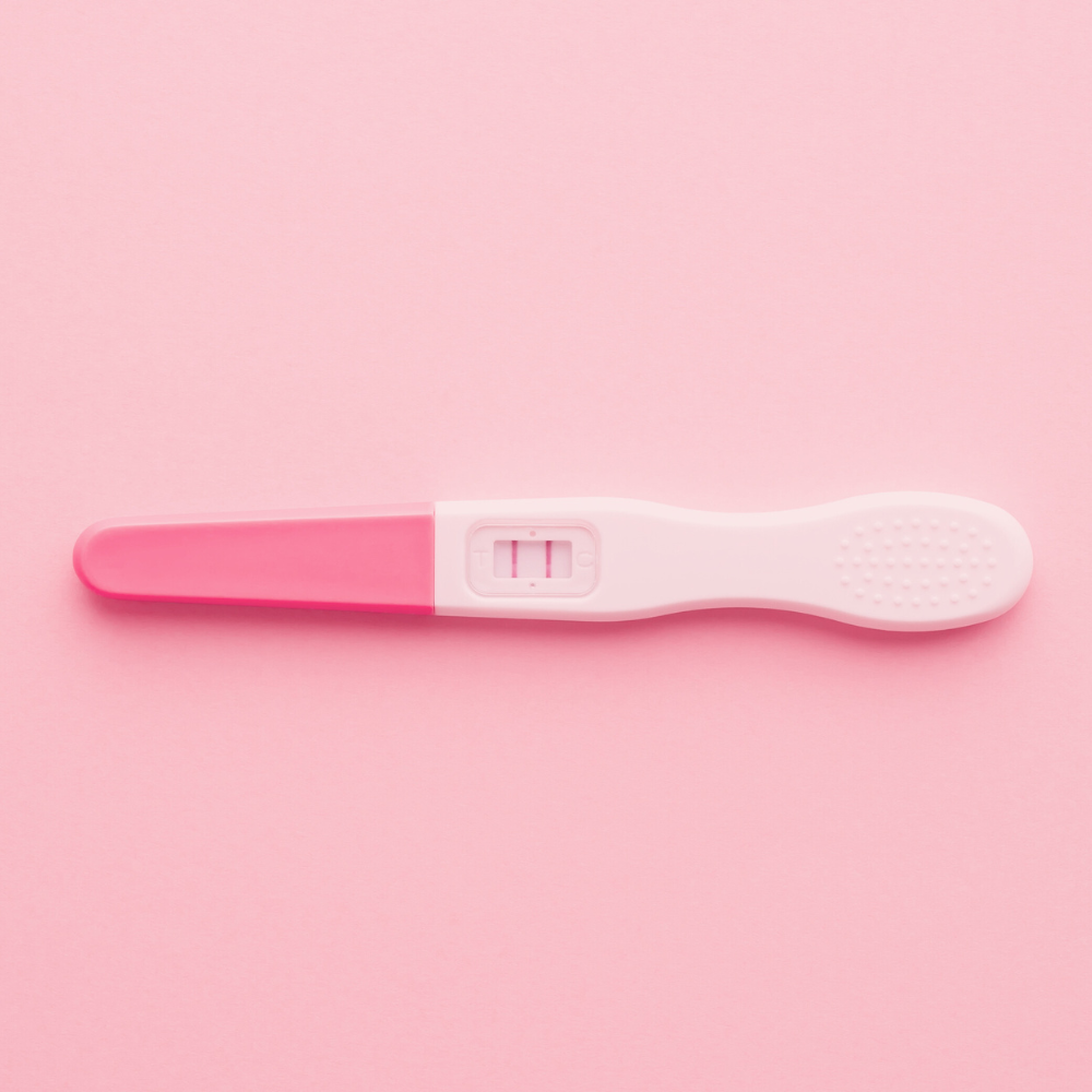 Pregnancy test showing a positive result on a pink background