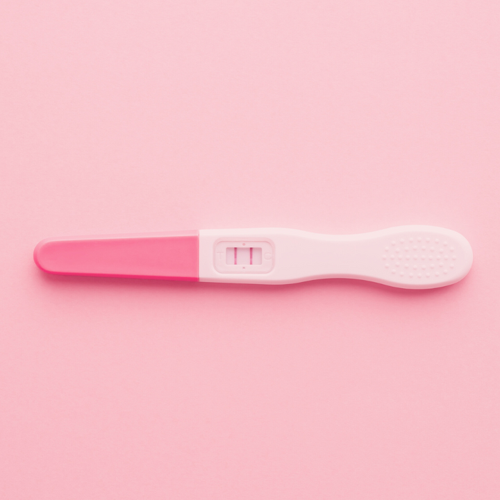 Pregnancy test showing a positive result on a pink background