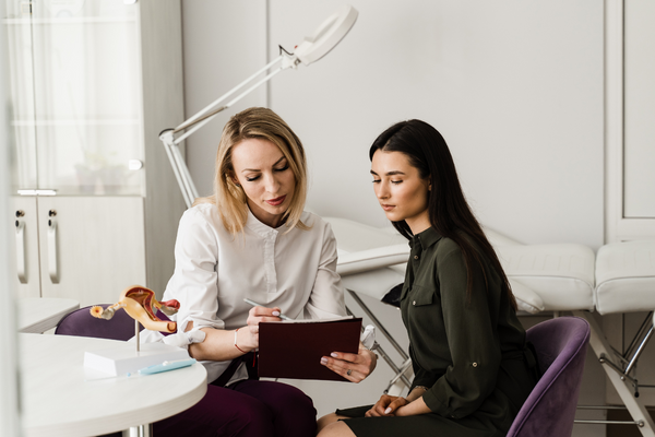 Doctor holding a uterus model while discussing results with a patient in a clinic
