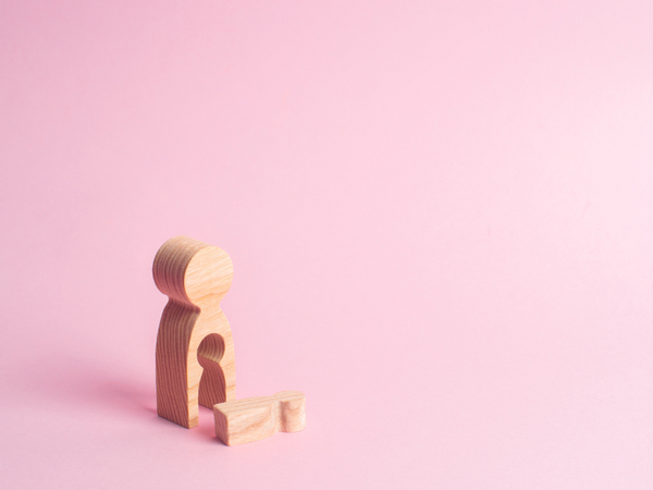 Wooden figures of an adult and child on a pink background