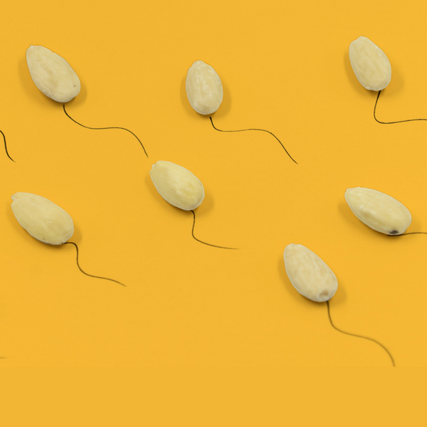 Almonds with drawn tails resembling sperm on a yellow background