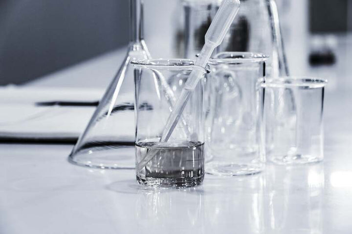 Laboratory beakers and a pipette with liquid samples on a lab counter