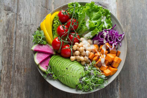 Colourful buddha bowl with avocado, cherry tomatoes, chickpeas, roasted sweet potato and shredded red cabbage