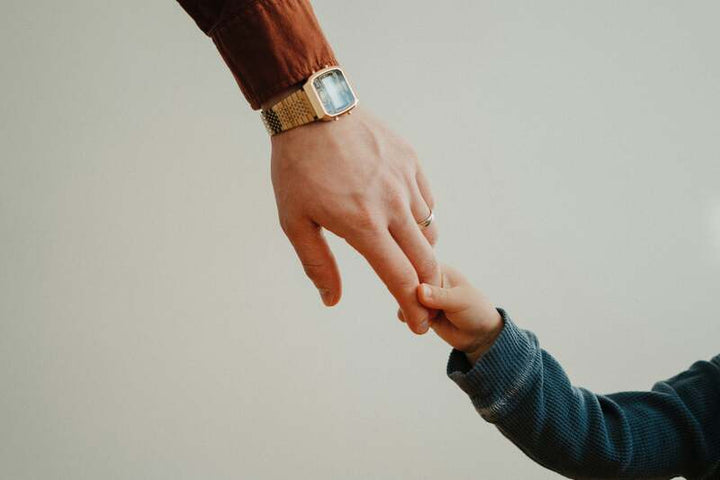 Adult hand reaching to hold a child's hand