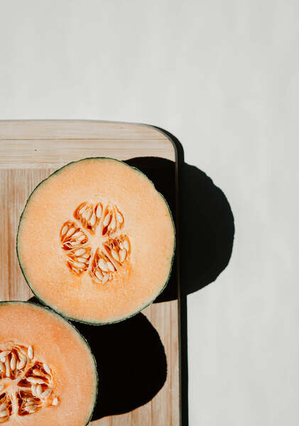 Sliced cantaloupe melon halves on a wooden board