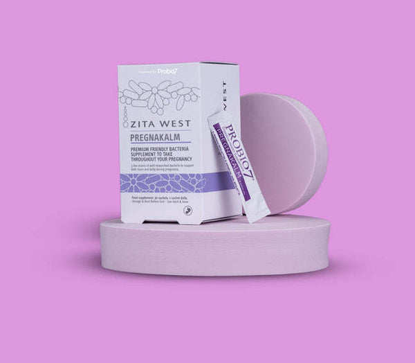 Zita West Pregnakalm probiotic supplement box and sachet on a lilac podium against a pink background