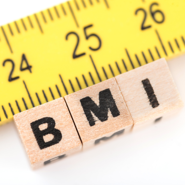 Wooden blocks spelling BMI beside a tape measure