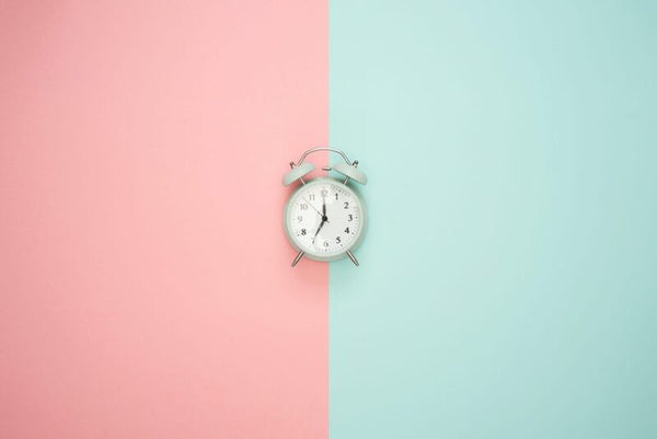 Vintage alarm clock centered against a pink and mint green split background