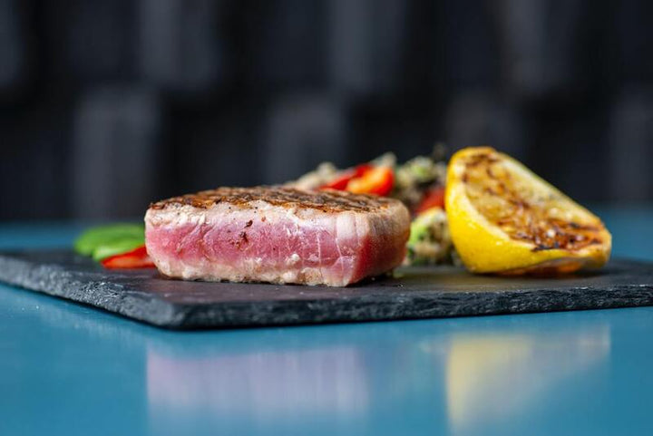 Seared tuna steak sliced and served with a grilled lemon wedge
