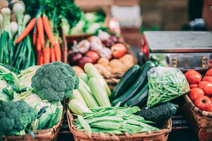 Fresh vegetables including broccoli, carrots, cucumbers and tomatoes at a market stall