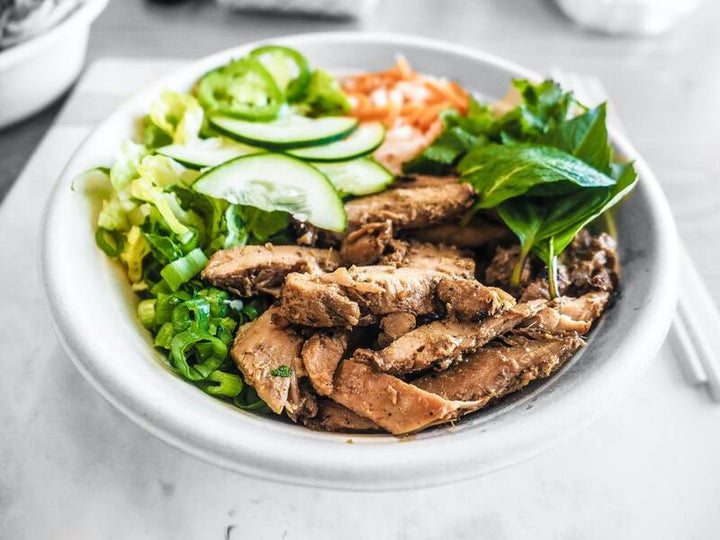 Bowl of sliced meat with lettuce, cucumber and herbs