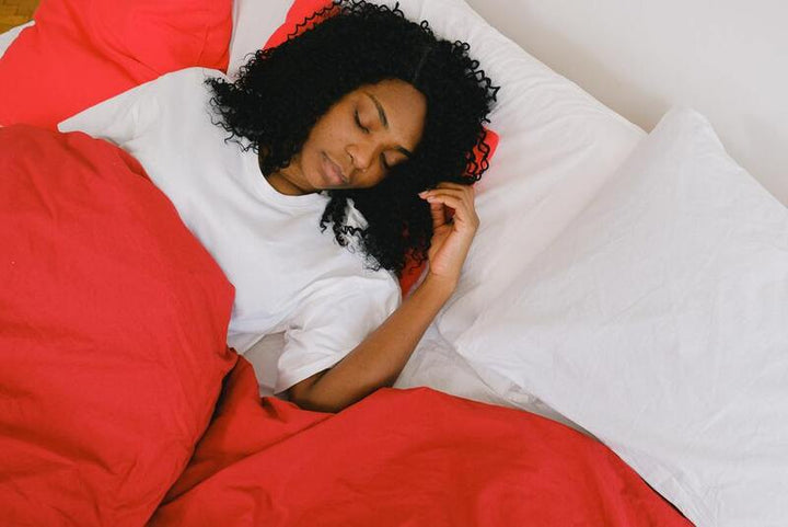 Woman sleeping peacefully in bed with white and red bedding