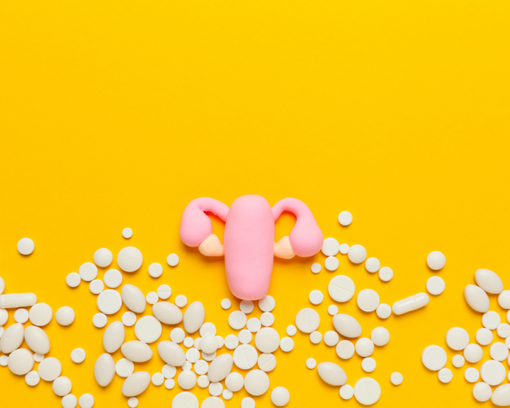 Illustration of a pink uterus surrounded by scattered white pills on a yellow background